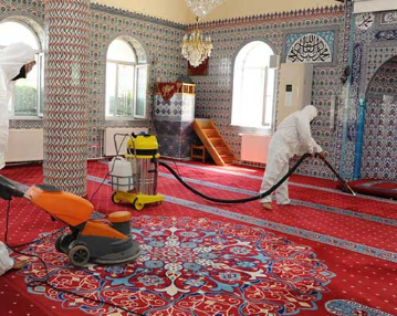 Cami halısını yerinde makine ile temizleyen bir görevli Cami halısını yerinde makine ile temizleyen bir görevli